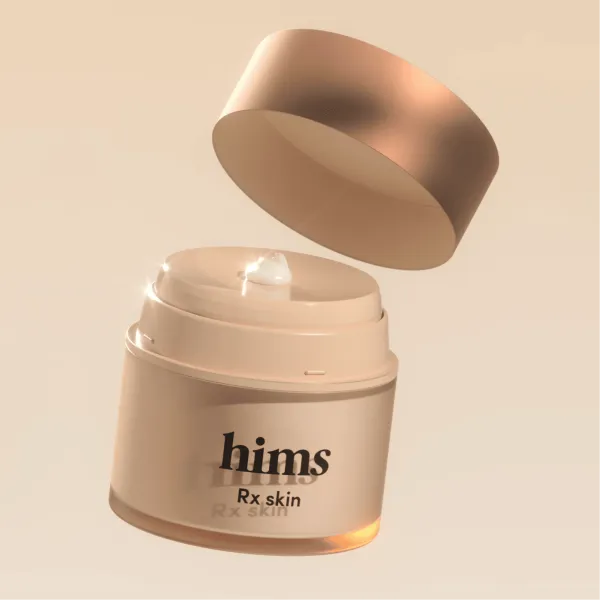 Hims' own photo of an open tan jar labeled Rx skin, with the lid lifted to show white cream inside.